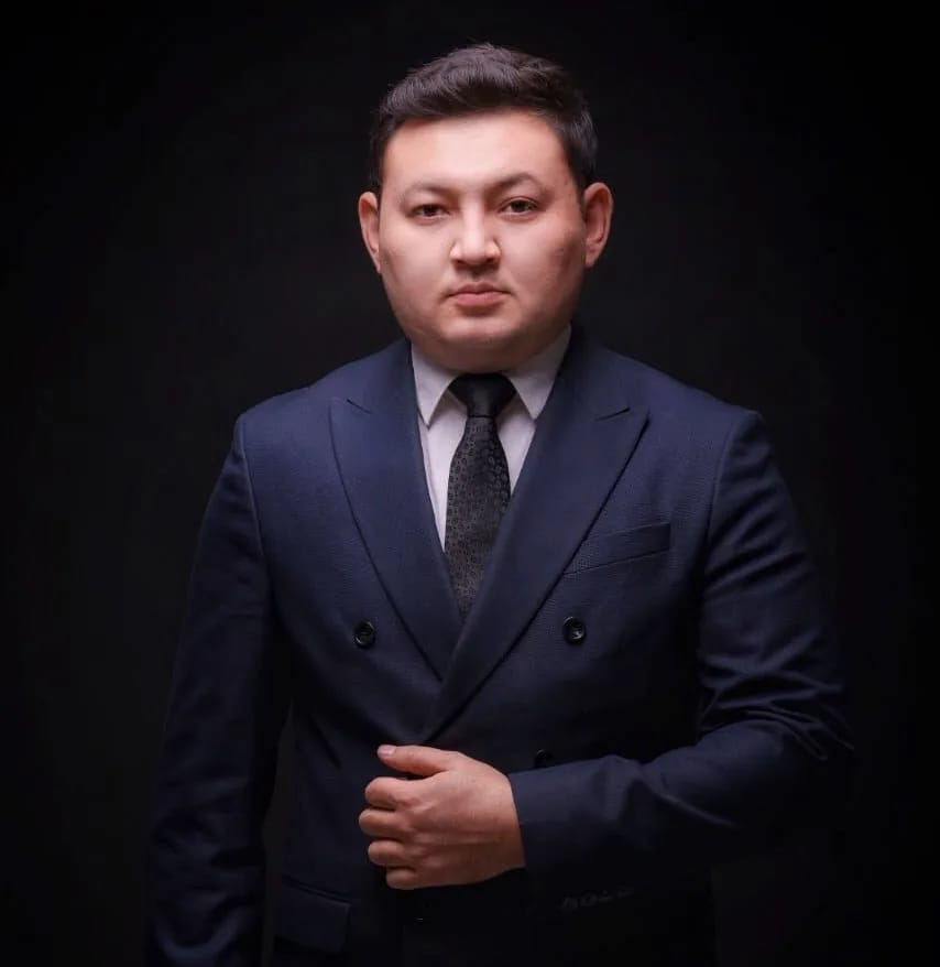 Алмас Абдрахимов, ведущий и тамада, в тёмно-синем двубортном костюме на чёрном фоне
